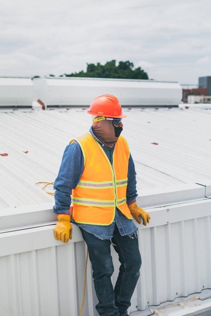 pexels photo 8853538 A construction worker wearing PPE gear leaning on a rooftop, showcasing safety at work.